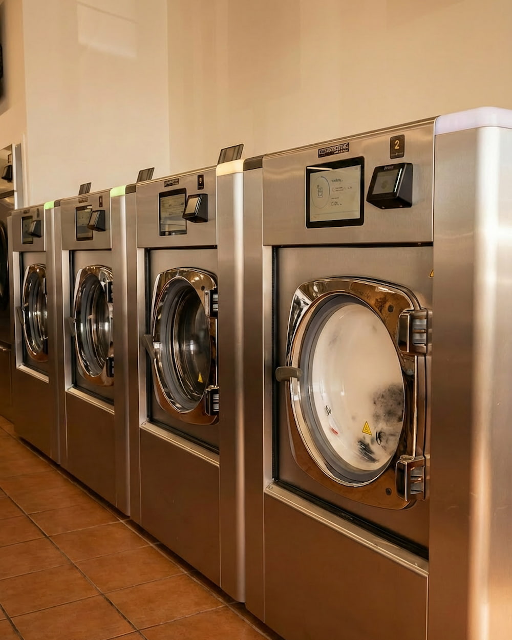 Row of stainless steel 40lb coinless washers with digital screens at Polanco Laundry in Arleta, San Fernando Valley